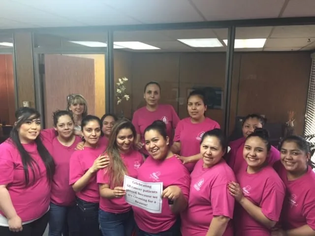 The DomesticAide cleaning team in the Tulsa office, holding a sign celebrating cancer patients served through Cleaning for a Reason