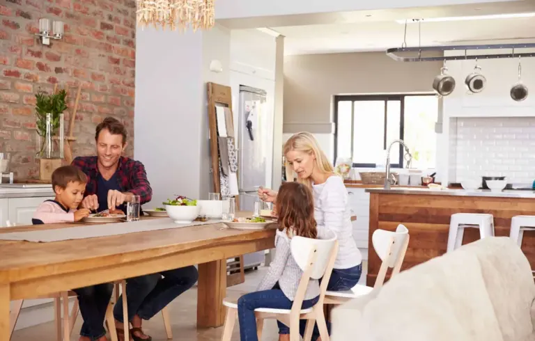 A family eating at a dining table in a clean open-plan kitchen