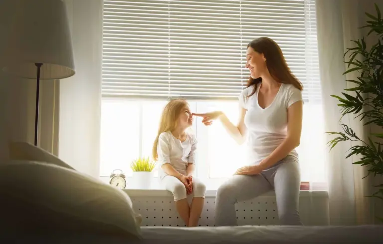 A parent and child sitting by a clean bedroom window in the morning light